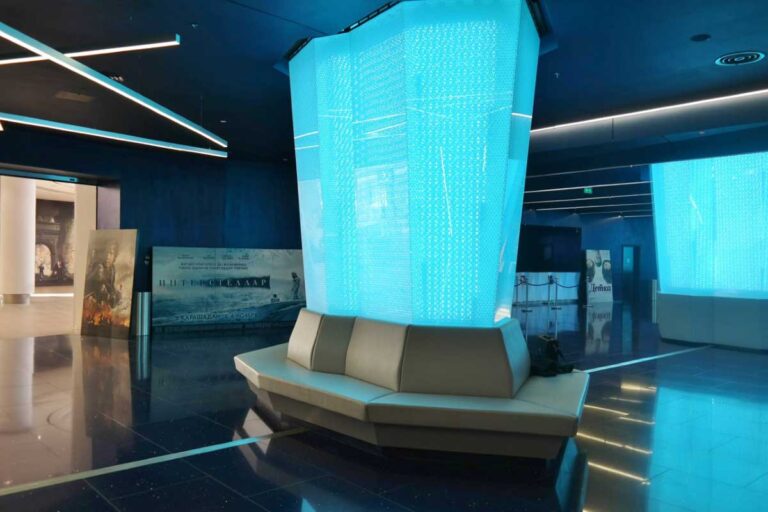 Lounge im Kino mit klaren Paneelen und blauer Beleuchtung für entspannte Atmosphäre